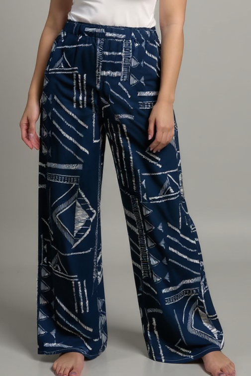 Woman wearing a white top and blue patterned pants on a gray background