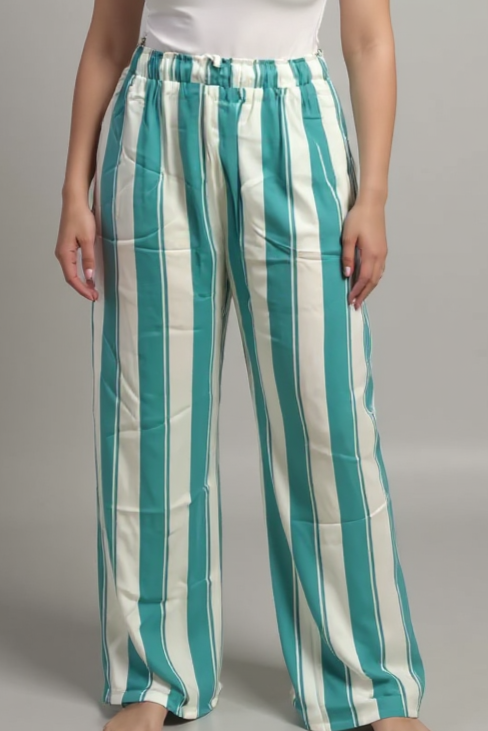 Woman wearing a white t-shirt and green and white striped pants on a gray background