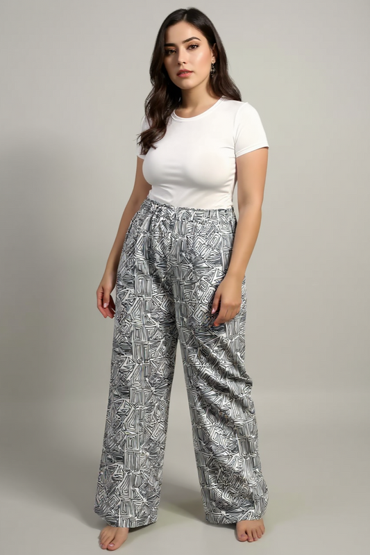 Woman wearing a white t-shirt and patterned pants on a plain background