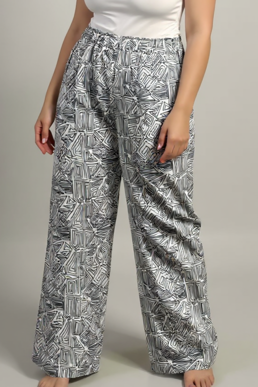 Woman wearing a white t-shirt and patterned pants on a plain background