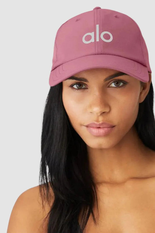 Woman wearing a pink 'alo' cap against a white background