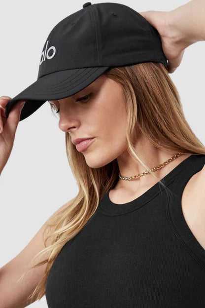 Woman wearing a black cap and black top against a light gray background