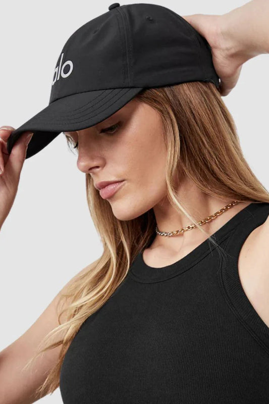 Woman wearing a black cap and black top against a light gray background